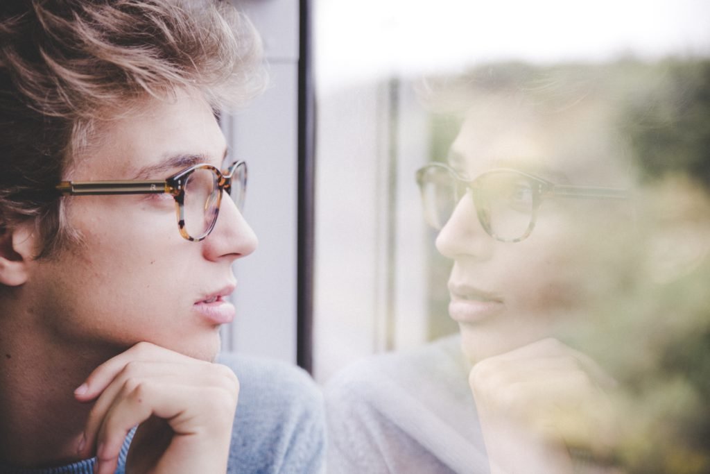 guy looking out a window with lush hair