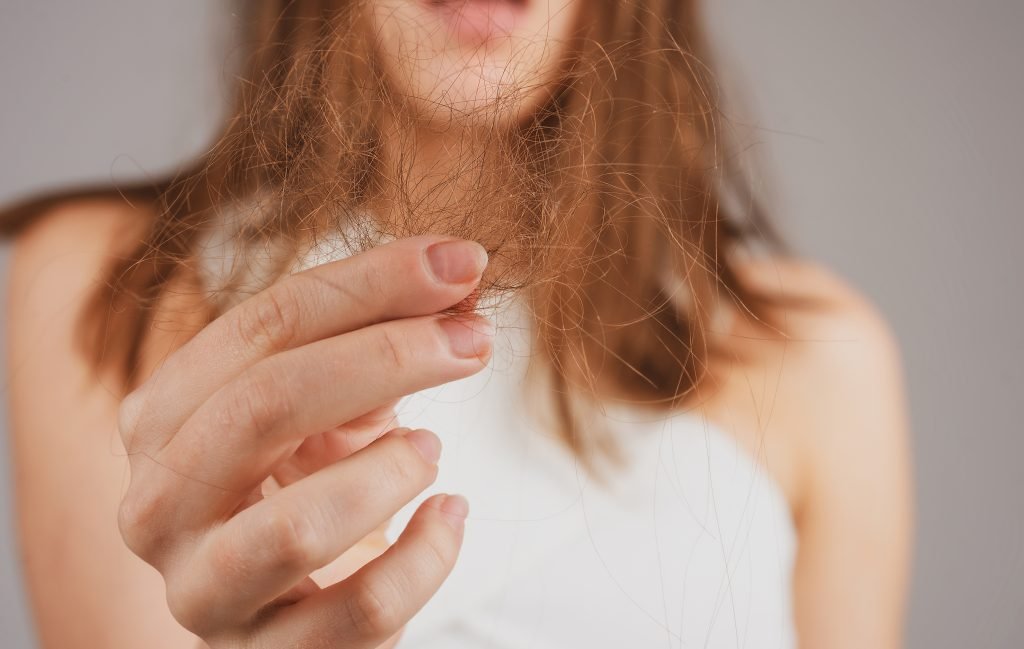 Sad woman looking at damaged hair, the hair loss problem.